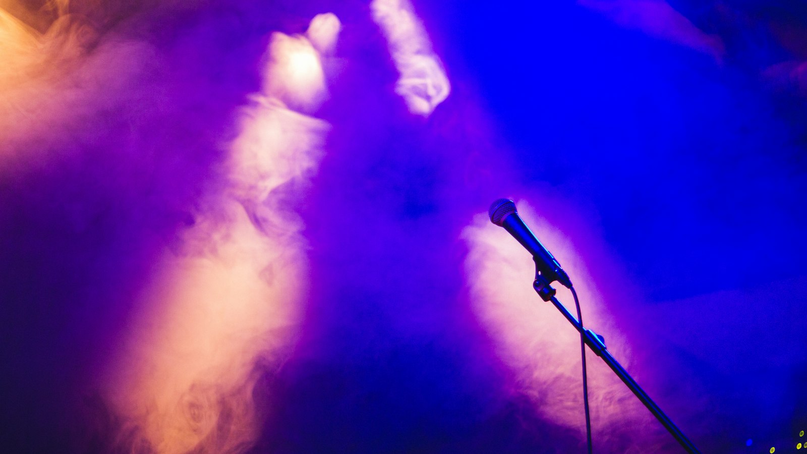 Microphone on a stage with purple lights — konuşmacı tanıtım metni